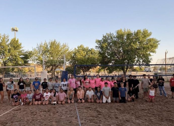Teen volleyball players compete on a sand court during a co-ed tournament.