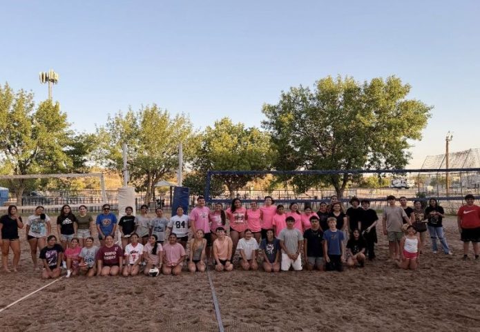 Teen volleyball players compete on a sand court during a co-ed tournament.