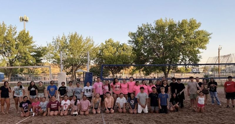 Teen volleyball players compete on a sand court during a co-ed tournament.