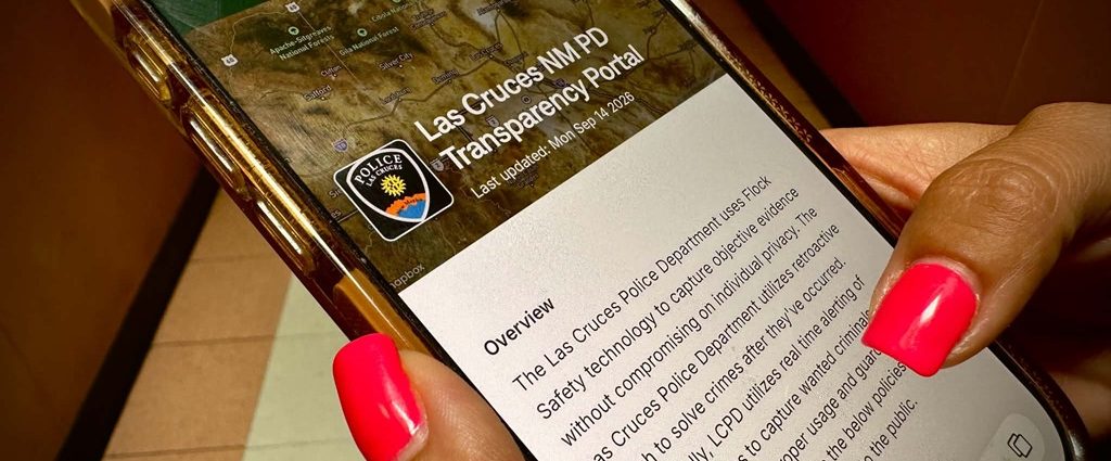 A person holds a phone displaying a Las Cruces information page.